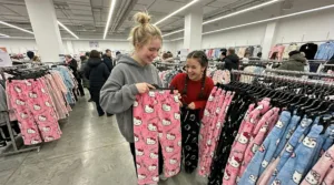 2 girls shopping for hello kitty pants in a store where one is holding a bubblegum color and the other a black one.